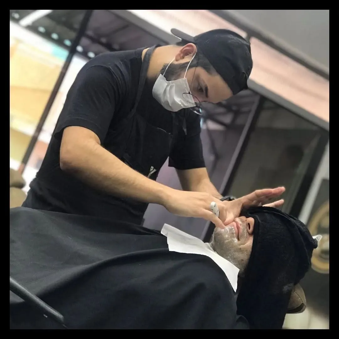 Barbeiro fazendo a barba de um cliente