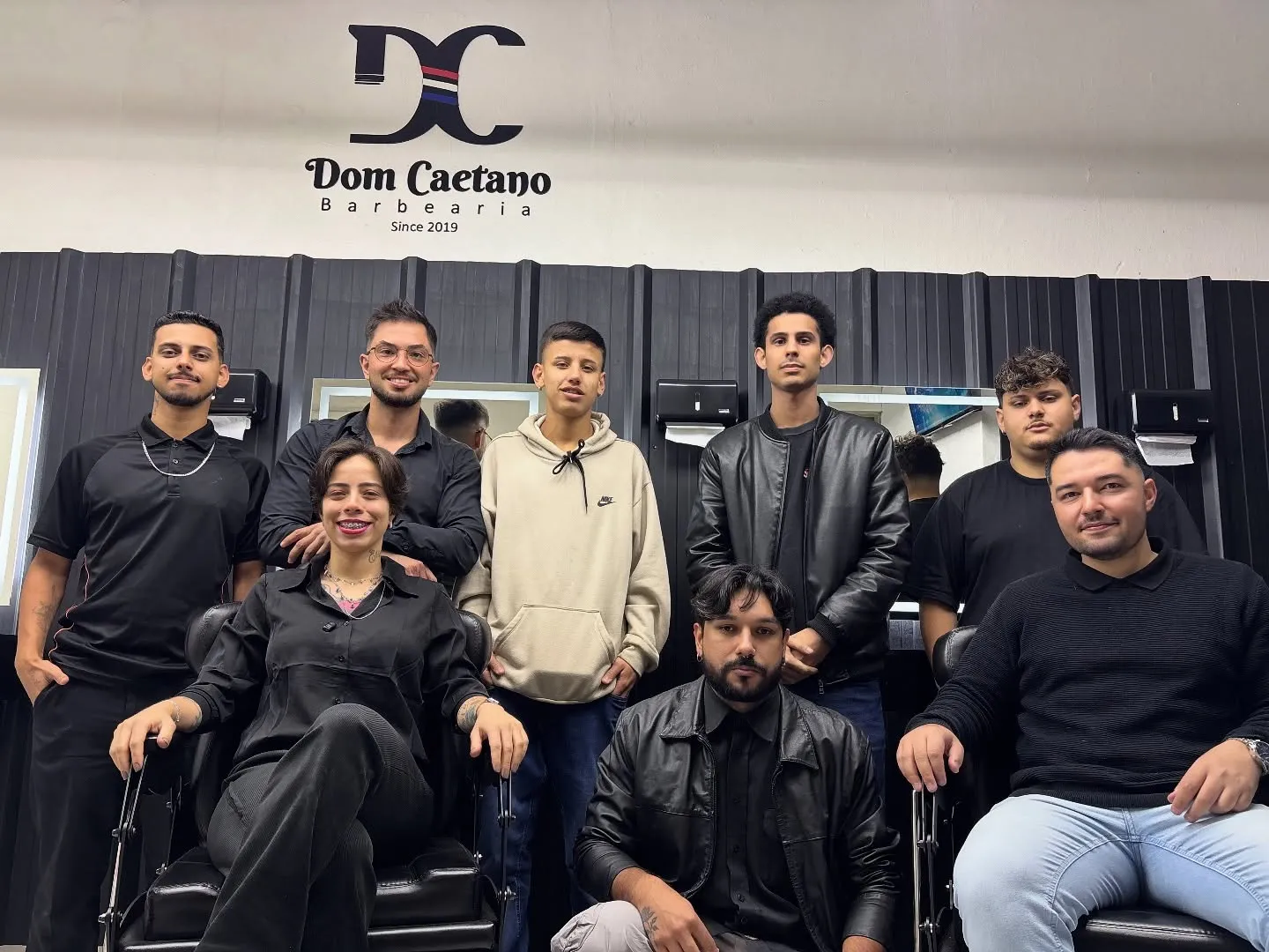 A equipe reunida na barbearia, sob a placa da Dom Caetano