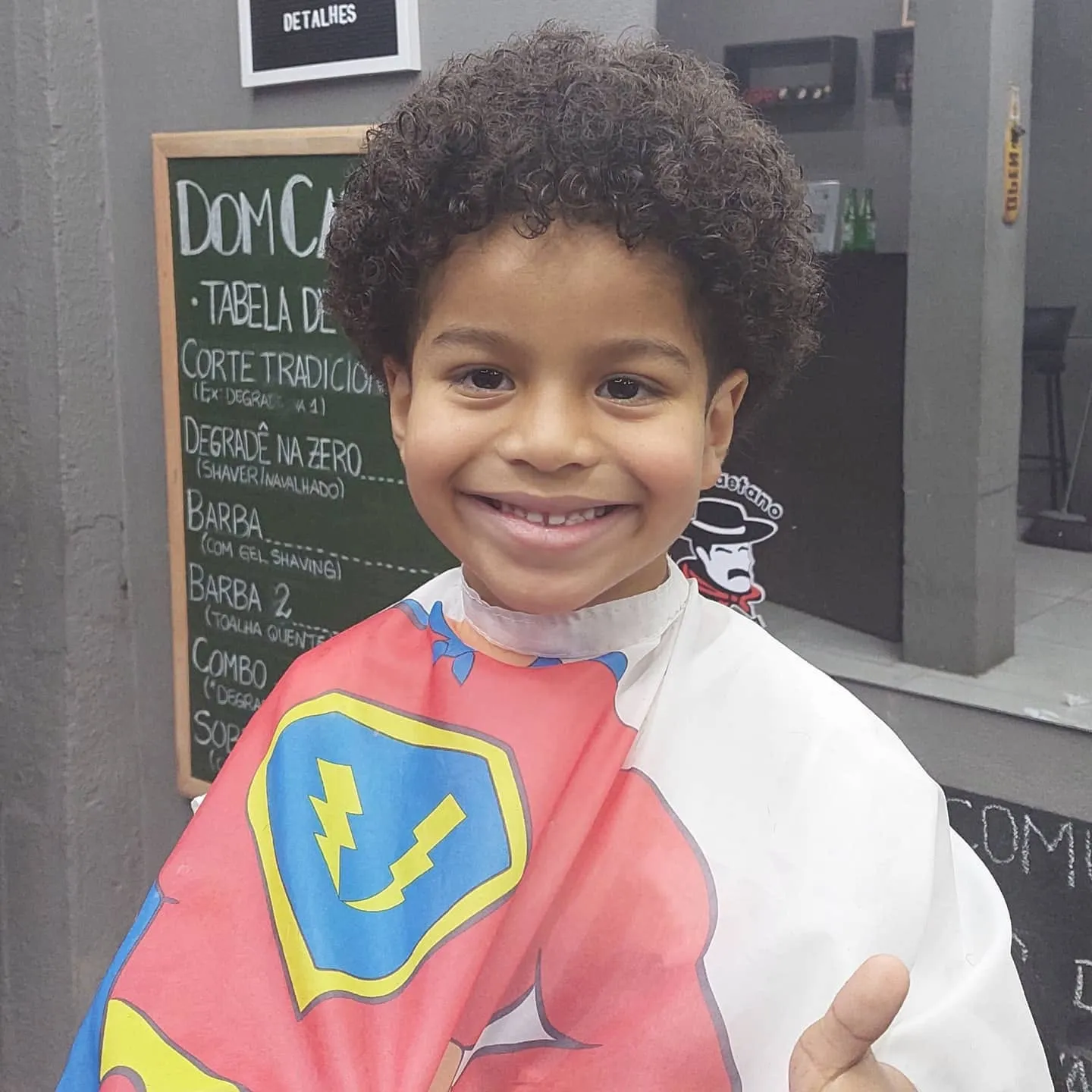 Criança sorrindo na cadeira, de capa de super-herói