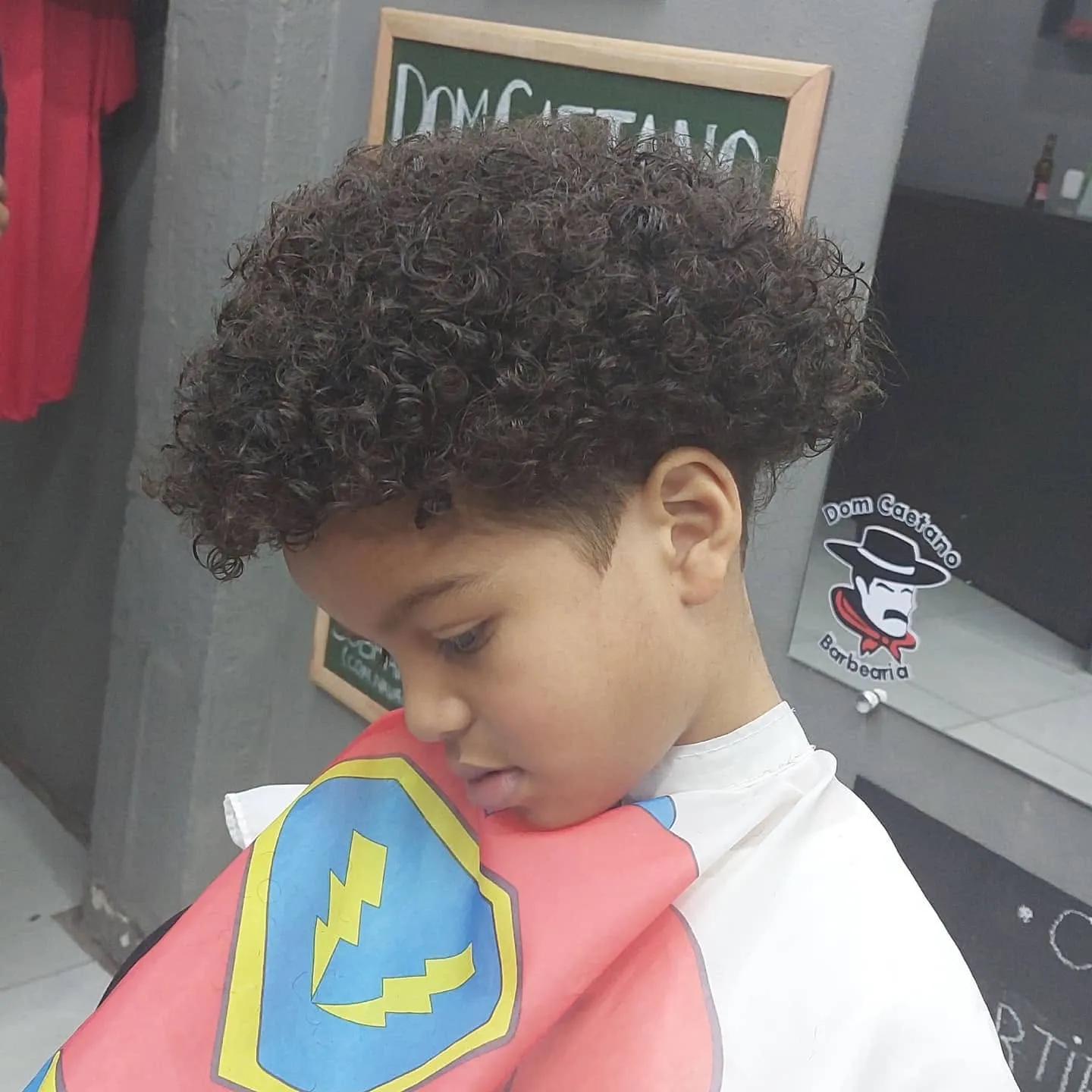 Criança de capa de super-herói durante o corte